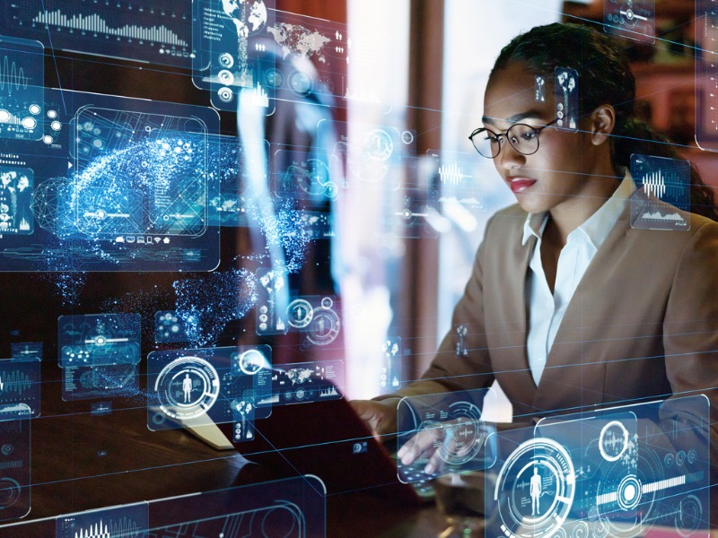 Une femme devant un ordinateur. En transparence on voit pleins d'applications technologiques, comme un logiciel de reconnaissance d'empreinte, etc.